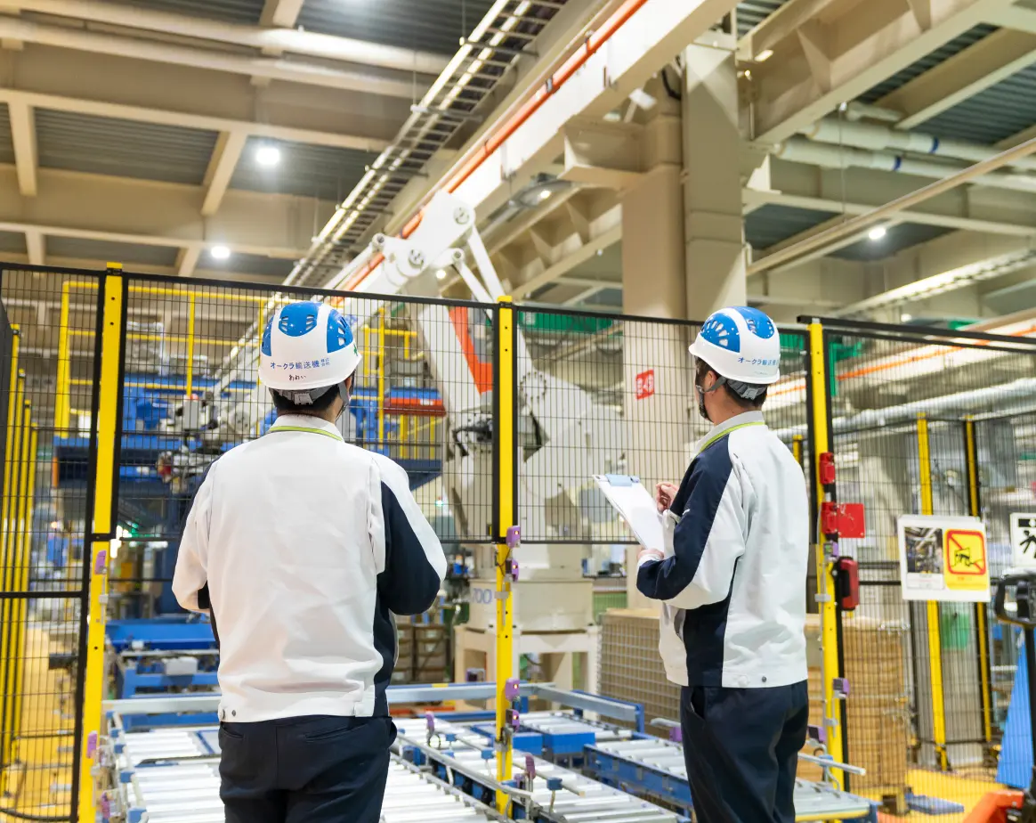 工場内でロボットシステムを点検するオークラ輸送機の社員2名